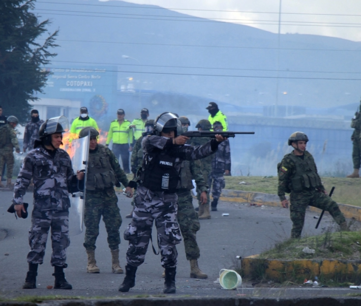 Des militaires et la police avec un militaire qui pointe son arme