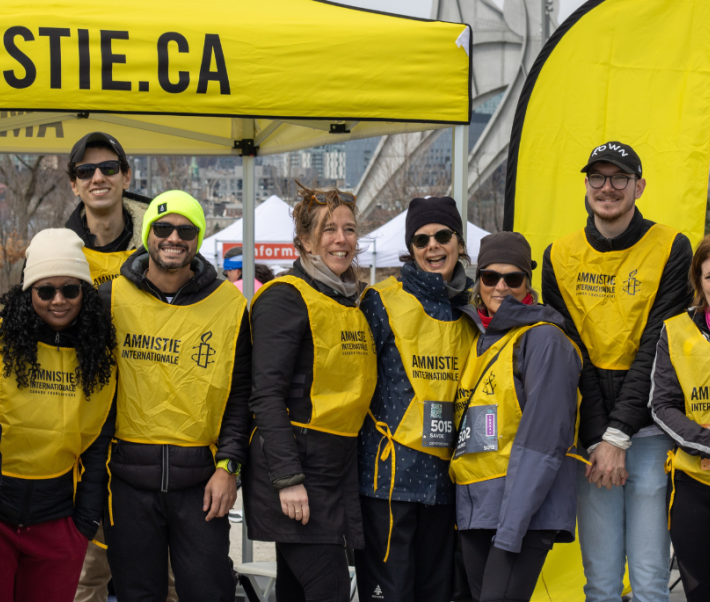 Les 12 membres de l'équipe de course d'Amnistie internationale sont en ligne et sourient, après avoir complété la course des 21K de Montréal.