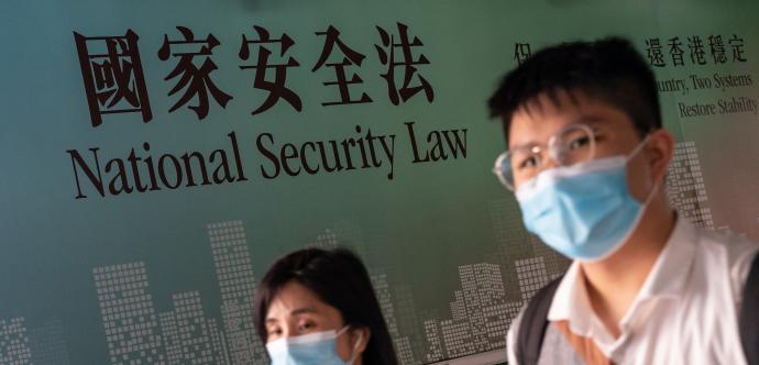 Deux personnes sont devant un écriteau inscrit «National Security Law» en Anglais et en Mandarin