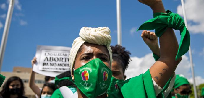 Une manifestante au point levée portant du vert.