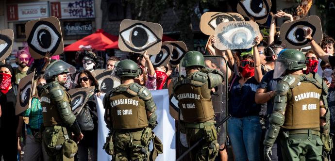 Des Carabineros devant une foule de manifestant·e·s