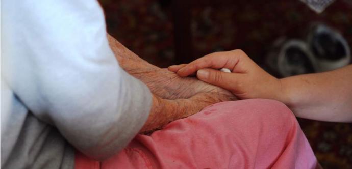 Une main est déposée sur le bras d'une personne âgée