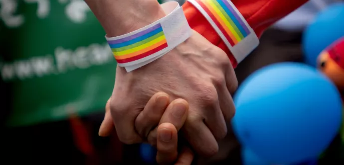 Une poignée de main avec des bracelets aux couleurs du drapeau LGBTI