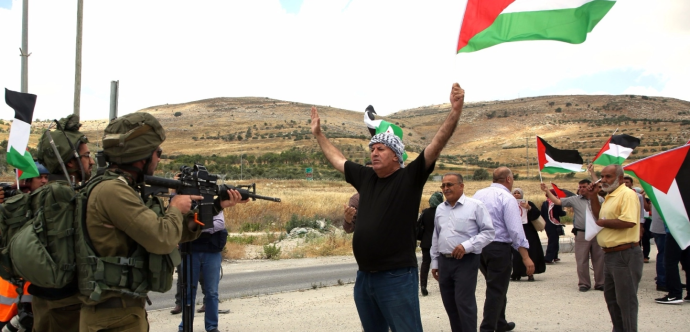 Des palestiniens avec drapeaux devant des militaires armés