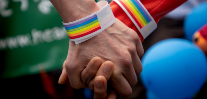 Deux mains se tenant l'une l'autre avec des bracelets arc-en-ciel.