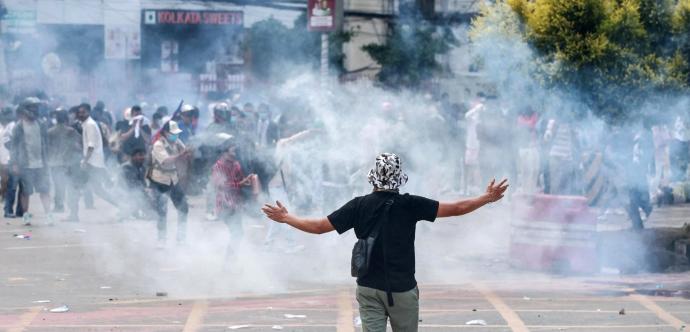Homme de dos avec les bras ouverts vers le ciel et du gaz autour de lui dans la rue en plein jour 
