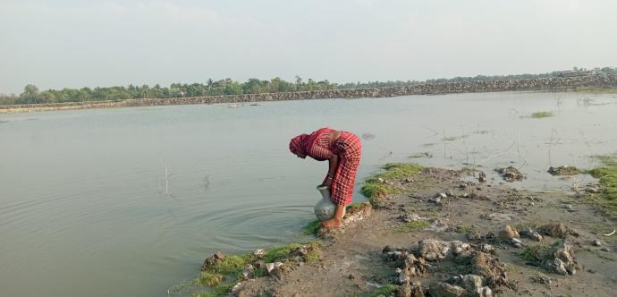 femme au bord d'un lac sale qui puise de l'eau 