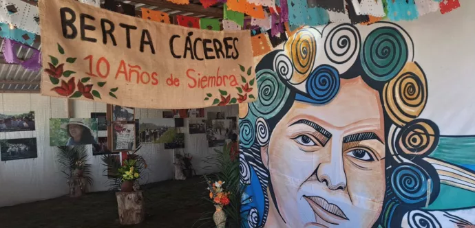 Murale avec un visage de femme et banderole avec un message rappelant la mort de Berta.