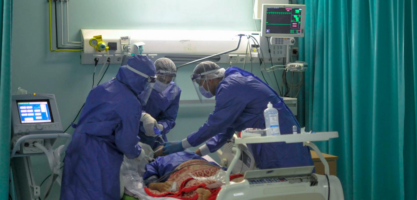 trois professionnel·le·s de la santé en tunique protective intubent un patient dans un hoptial du Caire. 