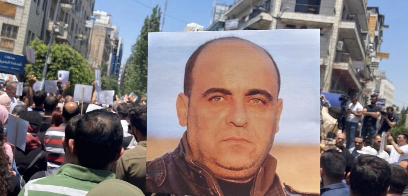 Manifestant·e·s tenant une affiche avec le portrait de Nizar Banat.