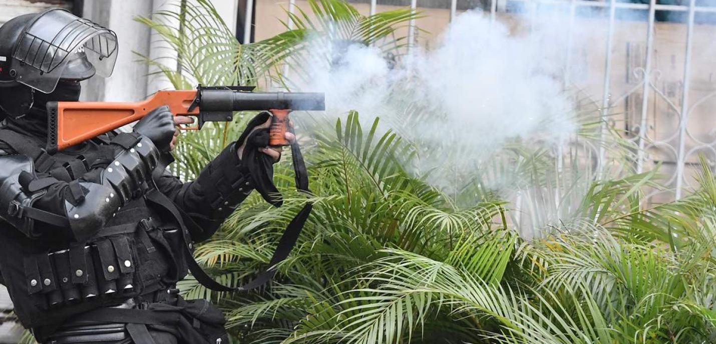 Une personne habillée en uniforme d'opération tactique lance un projectile.