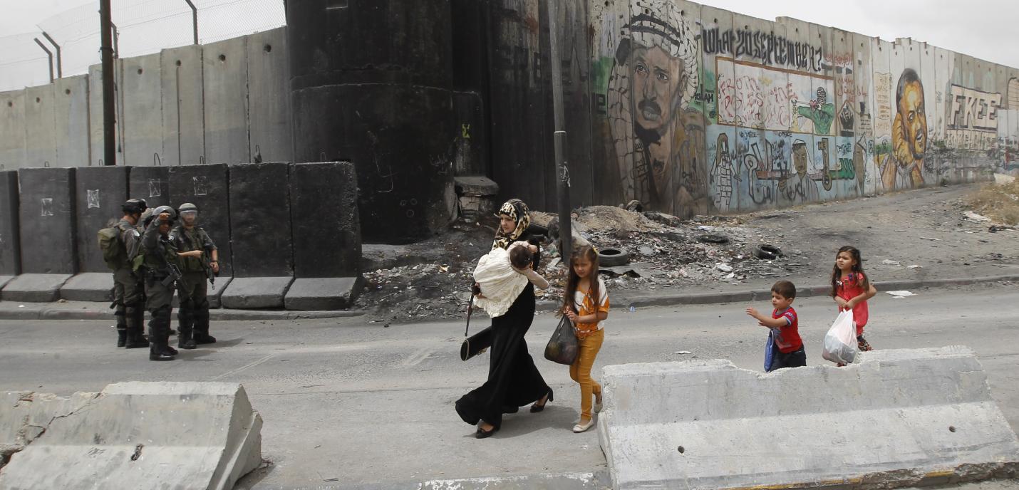 Une femme et des enfants palestiniens s’apprêtent à traverser le point de passage de Qalandiya, qui relie Ramallah à Jérusalem-Est, toutes deux situées en Cisjordanie occupée, afin de rejoindre le site de la mosquée d'Al Aqsa, à Jérusalem-Est, pour les premières prières du vendredi du ramadan, mois sacré pour les musulmans, le 2 juin 2017