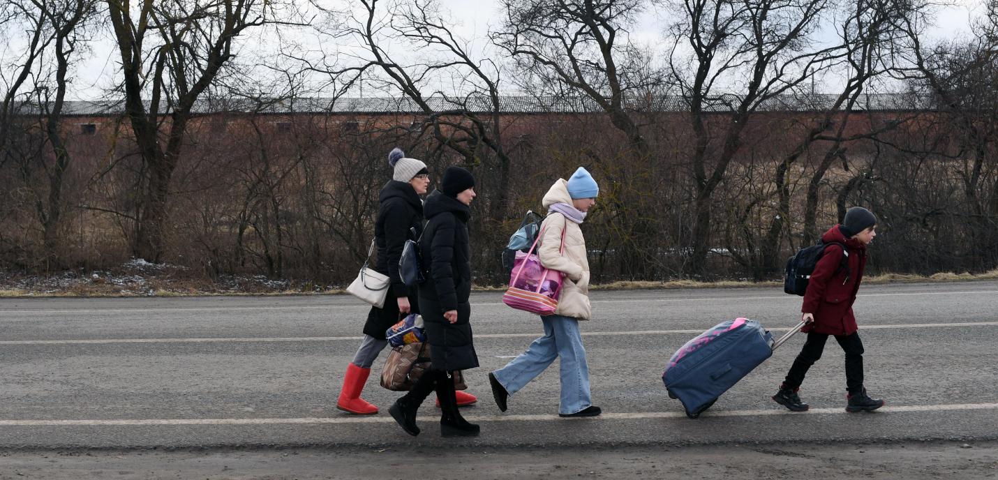 Des migrants marchent sur une route avec leurs affaires 