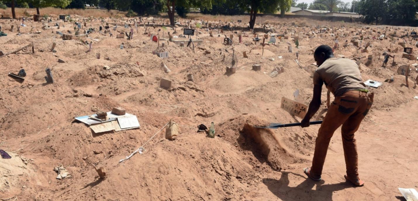 Une personne creuse le sol avec une pelle dans ce qui semble être un cimetière