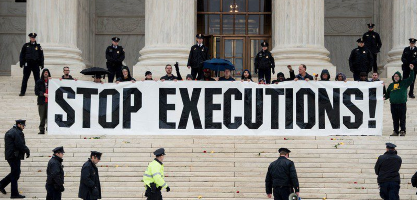 Des manifestants tiennent une banderole "Stop Executions" devant un grand bâtiment