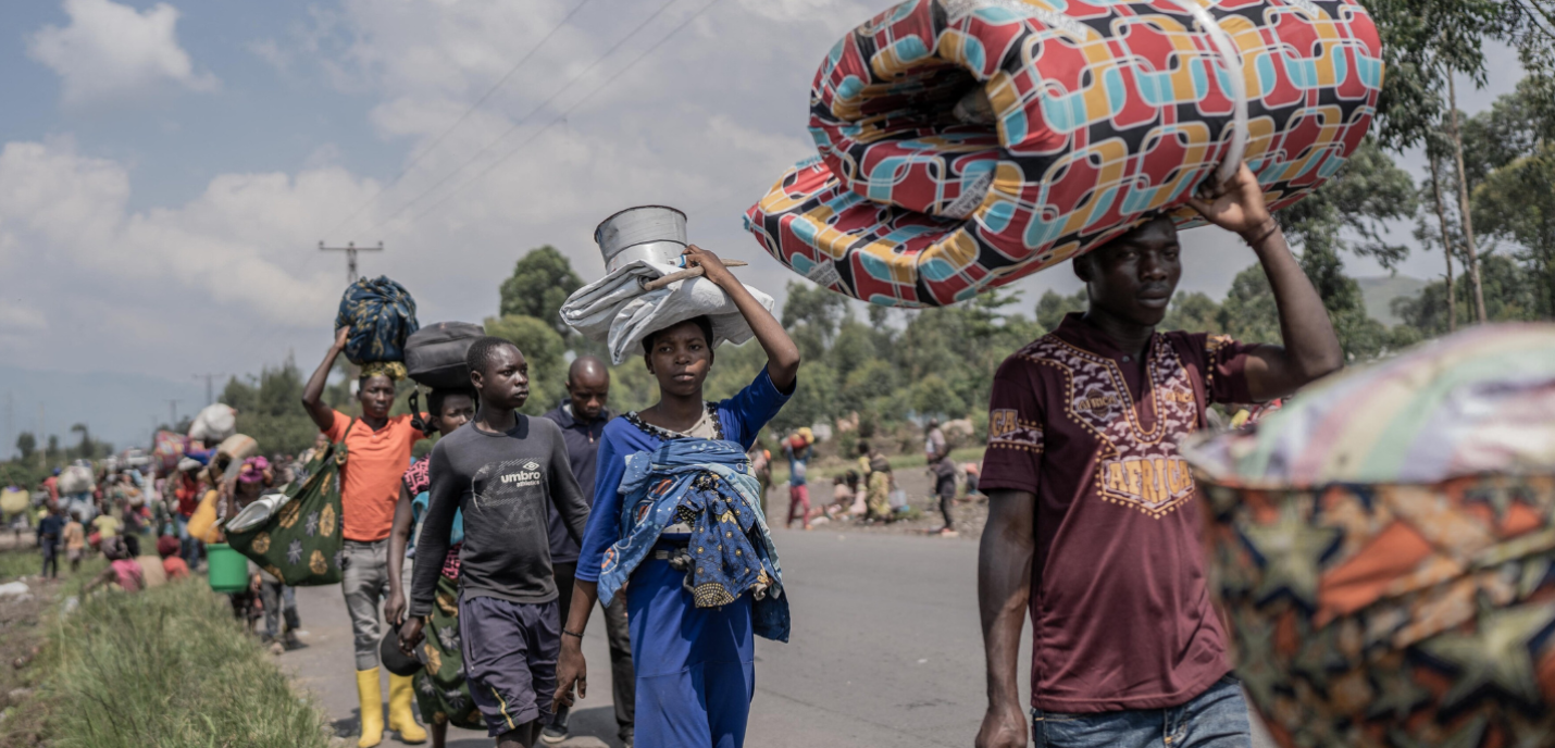 Des personnes transportent certains de leurs biens alors qu'elles fuient le territoire de Masisi suite aux affrontements entre les rebelles du M23 et les forces gouvernementales, sur une route près de Sake.