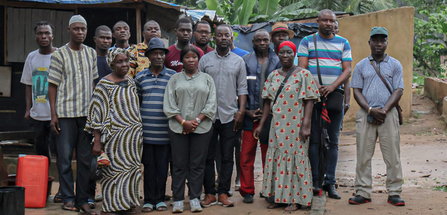 Des fermiers Ivoiriens sont regroupés pour la photo, le regard dénué d'émotions, dans un décor rappelant des bidonvilles