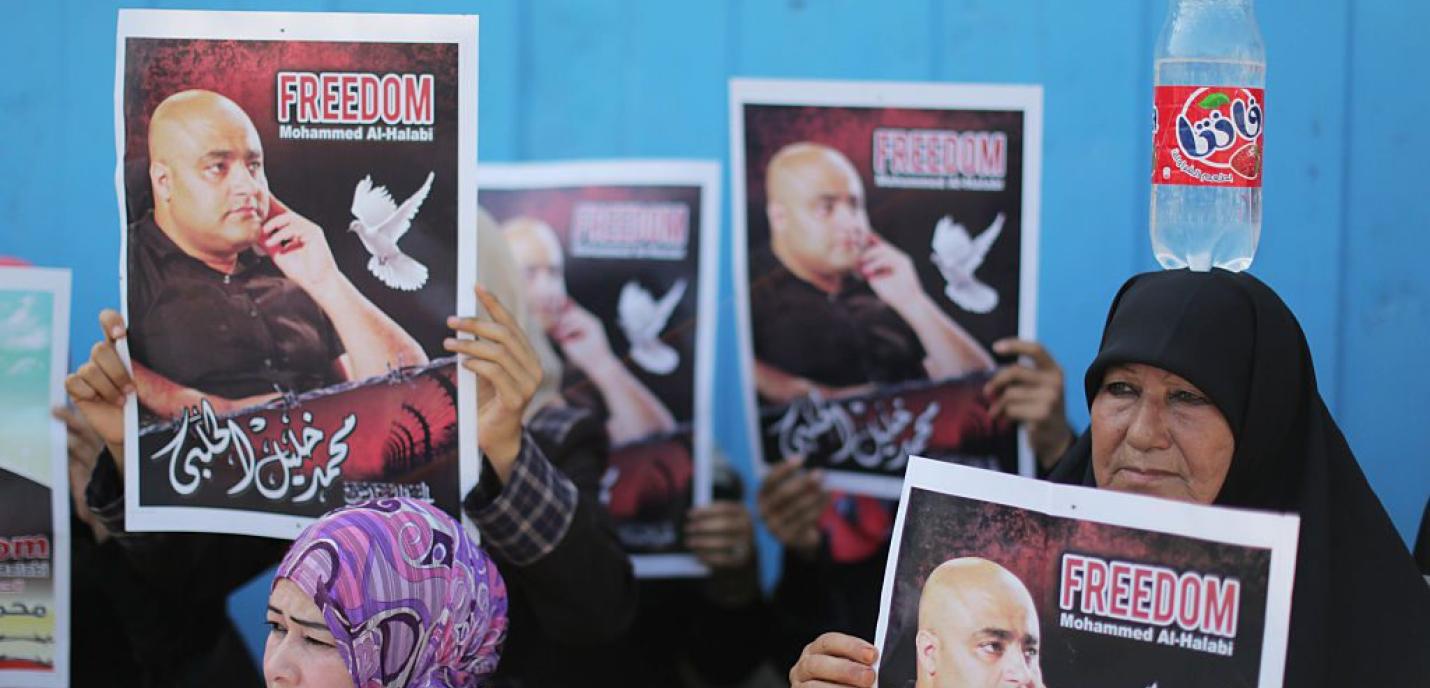 Un groupe de personnes manifestant, parmi lesquelles deux femmes tenant des pancartes avec l'inscription «Freedom Mohammed Al-Halabie» et une photo de l'homme concerné.