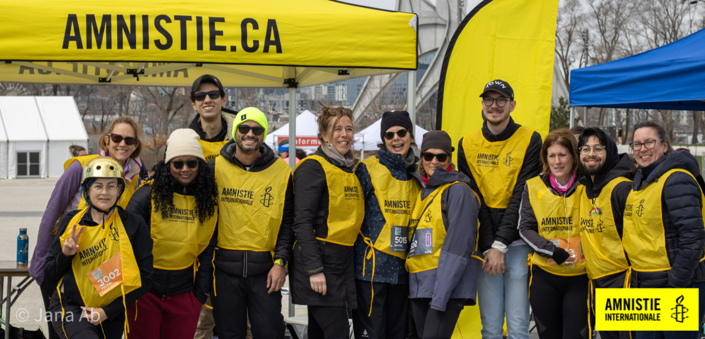 Les 12 membres de l'équipe de course d'Amnistie internationale sont en ligne et sourient, après avoir complété la course des 21K de Montréal.