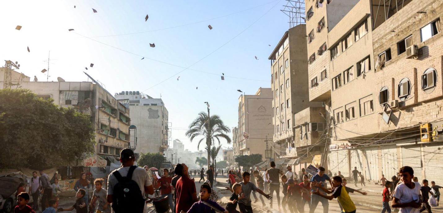 des choses qui tembent du ciel dans une ruelle avec des batiments détruits à gaza 