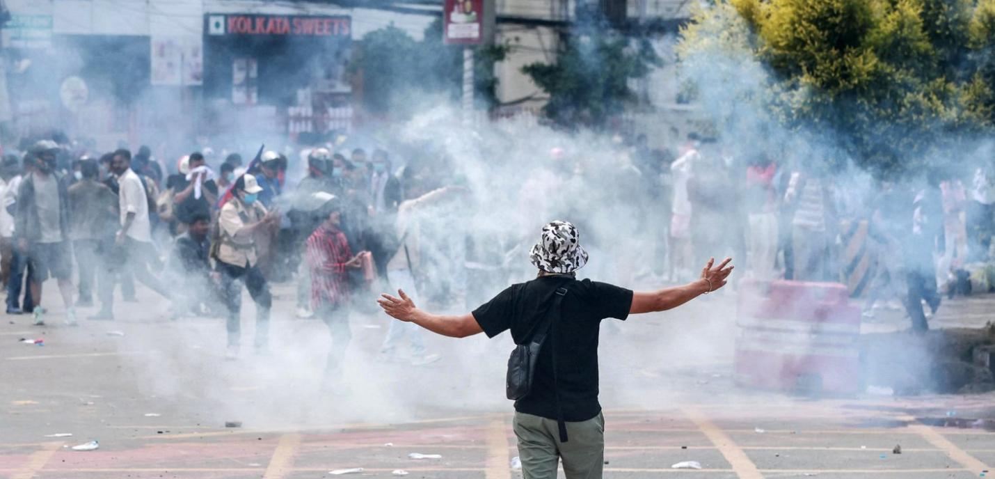 Homme de dos avec les bras ouverts vers le ciel et du gaz autour de lui dans la rue en plein jour 