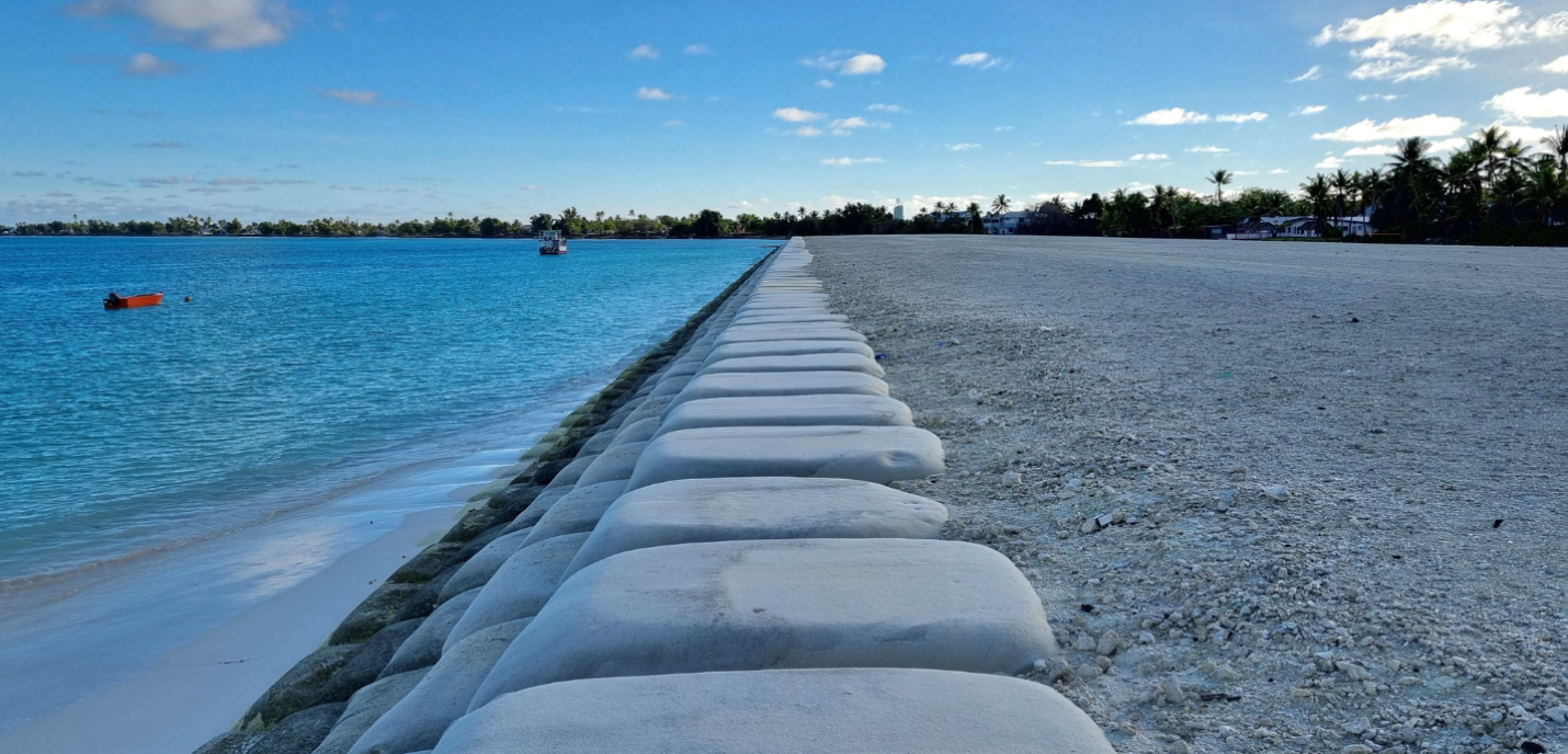Un projet de récupération de terres à Funafuti, prévu pour durer environ 25 ans, consiste à draguer du sable dans le lagon, à le placer dans de grands sacs qui restent en place jusqu’à un an avant que des plants soient plantés, puis, finalement, à construire des bâtiments afin que des personnes puissent s’installer sur cette nouvelle terre. Tuvalu est une nation insulaire du Pacifique dont la population subit directement les effets d’un climat déstabilisé – notamment l’érosion côtière, l’inondation par l’ea