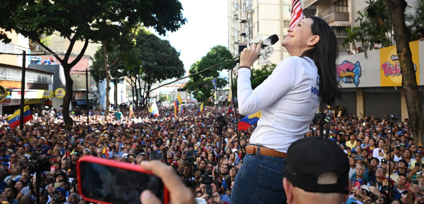 femme qui parle dans un micro sur une plateforme entourée par une foule de gens