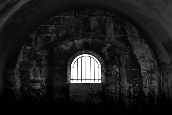 Une cellule de prison sombre avec une fenêtre avec de la lumière