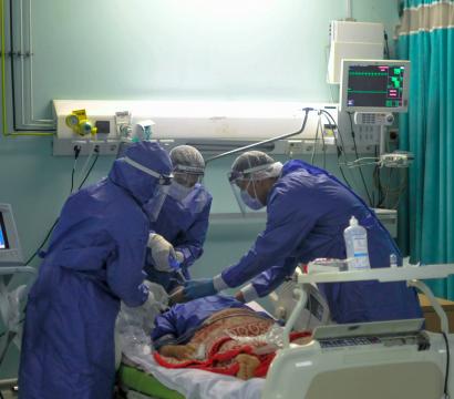 trois professionnel·le·s de la santé en tunique protective intubent un patient dans un hoptial du Caire. 