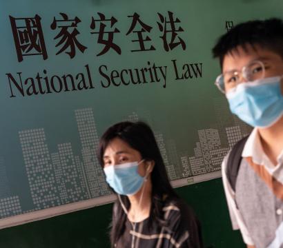 Deux personnes sont devant un écriteau inscrit «National Security Law» en Anglais et en Mandarin