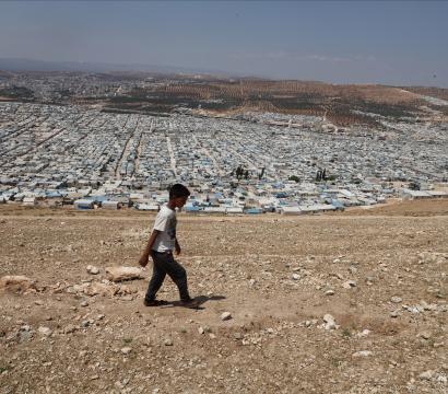 Un garçon marche devant des campements située au nord d'Idlib.