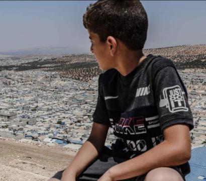 Un garçon devant un campement en Syrie