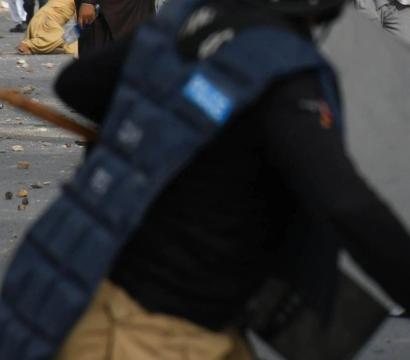 policier avec un baton à une manifestation au Pakistan