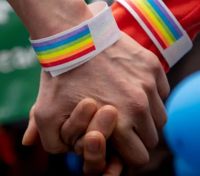 Une poignée de main avec des bracelets aux couleurs du drapeau LGBTI