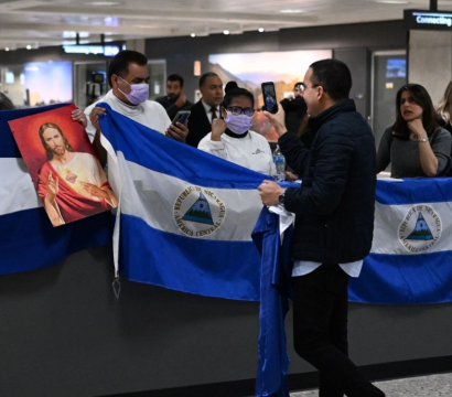 Des personnes qui attendent dans un aéroport avec des drapeaux du Nicaragua