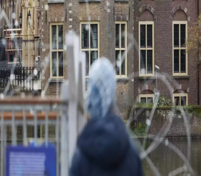 Une personne regardant à travers des fils de fer barbelé vers un bâtiment.