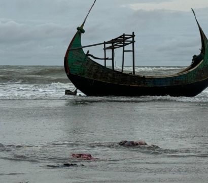 Bateau abandonné sur une plage avec des corps au sol en premier plan