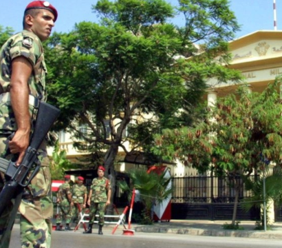 Un soldat tenant une arme dans la main droite, devant un tribunal militaire.