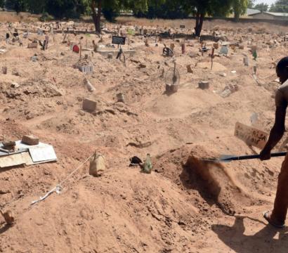 Une personne creuse le sol avec une pelle dans ce qui semble être un cimetière