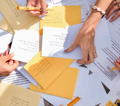 Des lettres sont entassées les unes sur les autres, avec des mains qui tiennent des stylos