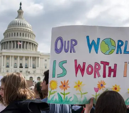 Une manifestation devant le capitole aux États-Unis, avec un premier plan une pancarte "Our World is worth it"