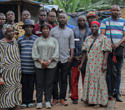 Des fermiers Ivoiriens sont regroupés pour la photo, le regard dénué d'émotions, dans un décor rappelant des bidonvilles