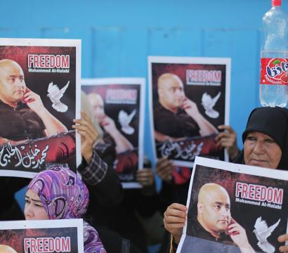 Un groupe de personnes manifestant, parmi lesquelles deux femmes tenant des pancartes avec l'inscription «Freedom Mohammed Al-Halabie» et une photo de l'homme concerné.