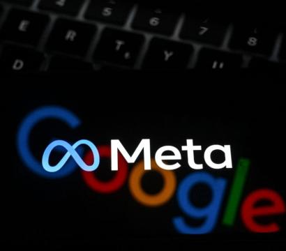 Un gros plan d’un écran affichant les logos de Meta (au premier plan, en blanc avec l’icône en forme d’infini bleu) et de Google (en arrière-plan, flou, avec ses lettres colorées), le tout posé sur un clavier d’ordinateur noir.